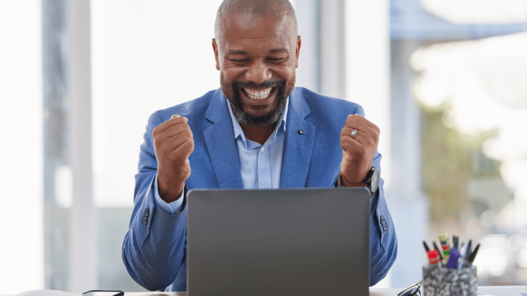 A person sitting at her desk with her hands in the air and a smile on her face