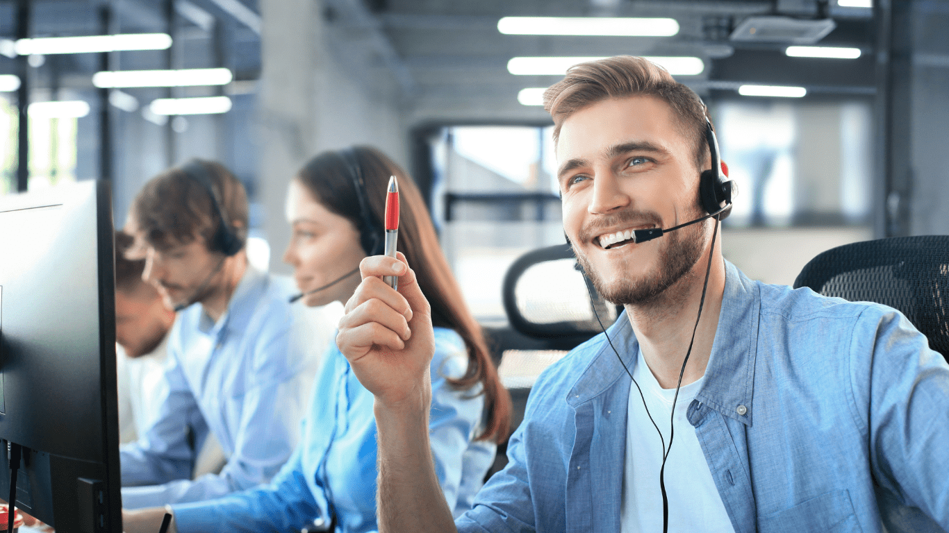 a smiling individual wearing a headset in a call center