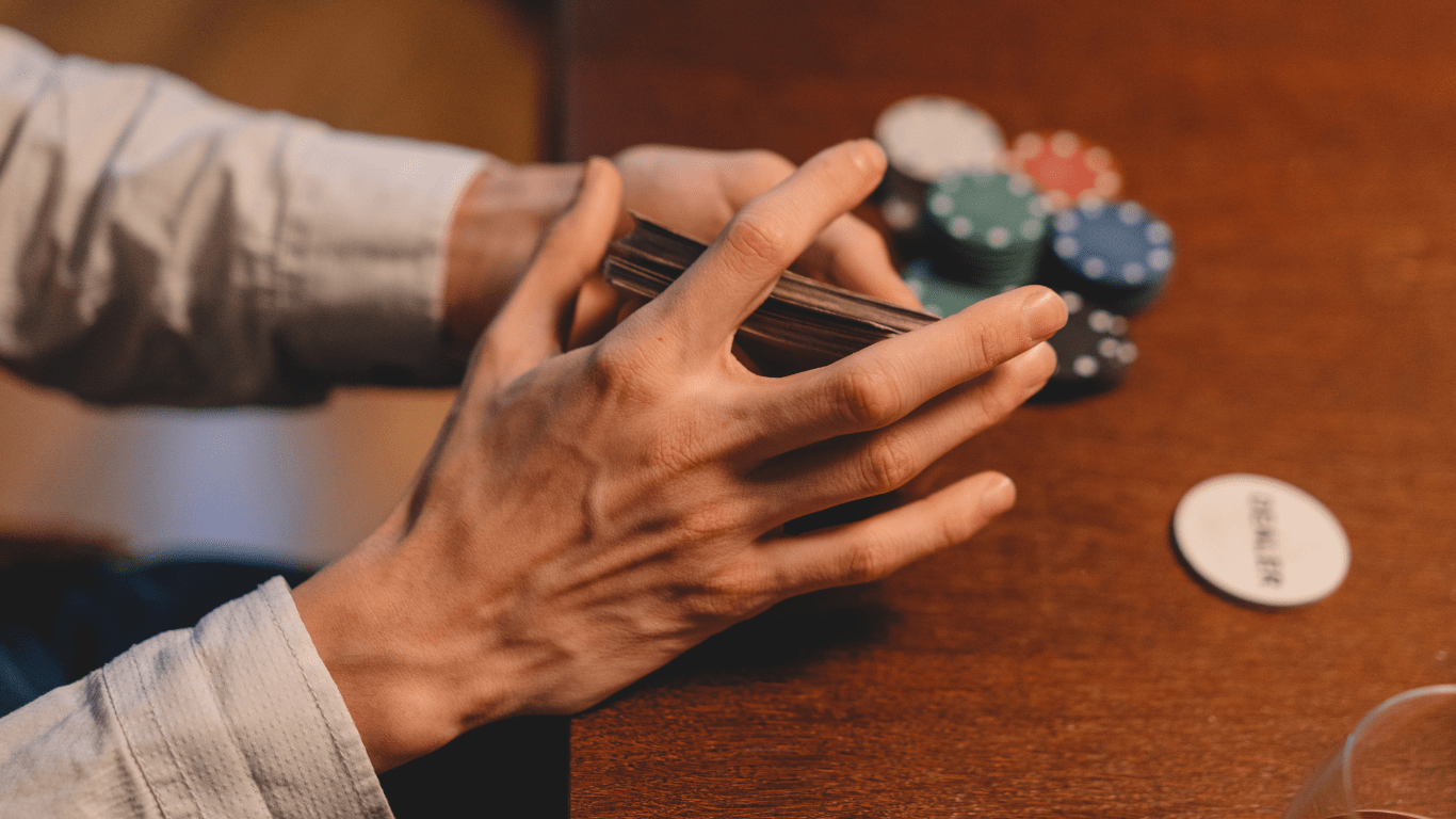 a person playing poker at a table with chips and a glass of whiskey