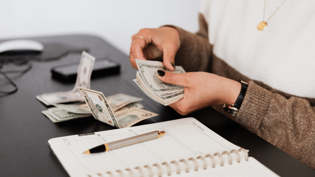 a person is holding money in front of a laptop