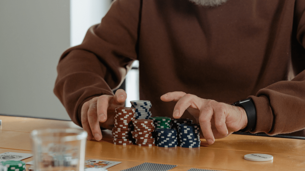 a person playing poker at a table with chips and a glass of whiskey