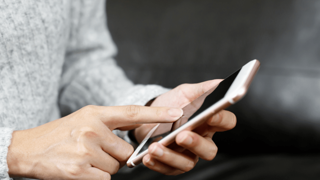 a person sitting on a couch holding a cell phone and looking at it