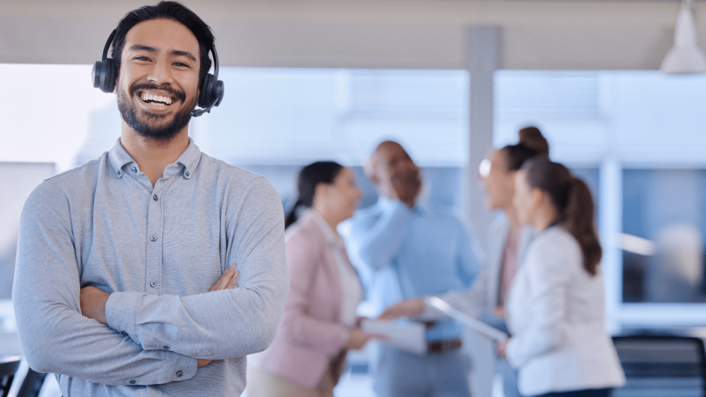 a smiling individual wearing a headset in a call center